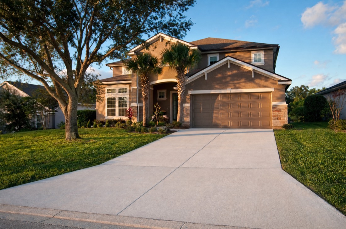 A freshly poured broom-finish concrete driveway in front of a two-story Central Florida home