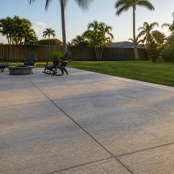 A newly poured concrete patio running from a screened lanai into a Florida backyard